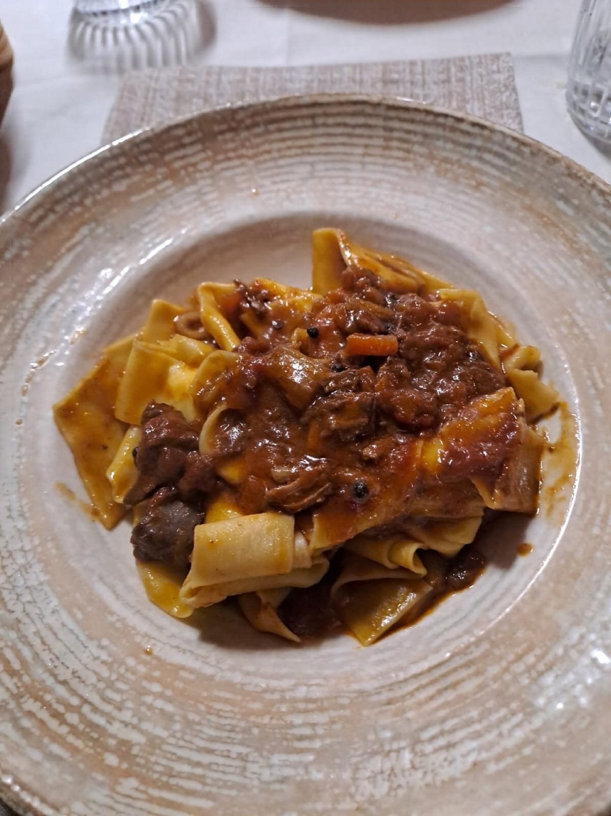 Pappardelle fresche al ragù di cinghiale su piatto in ceramica artigianale